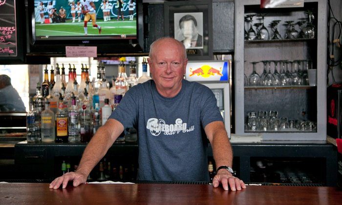 Behind the Scoreboard bar, with bottles and glassware on the back wall and a game on the television